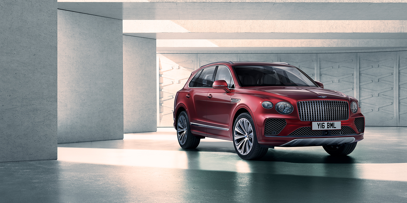 Bentley Hatfield Bentley Bentayga Atelier Edition SUV in Rubino Red paint front three quarter against textured concrete wall