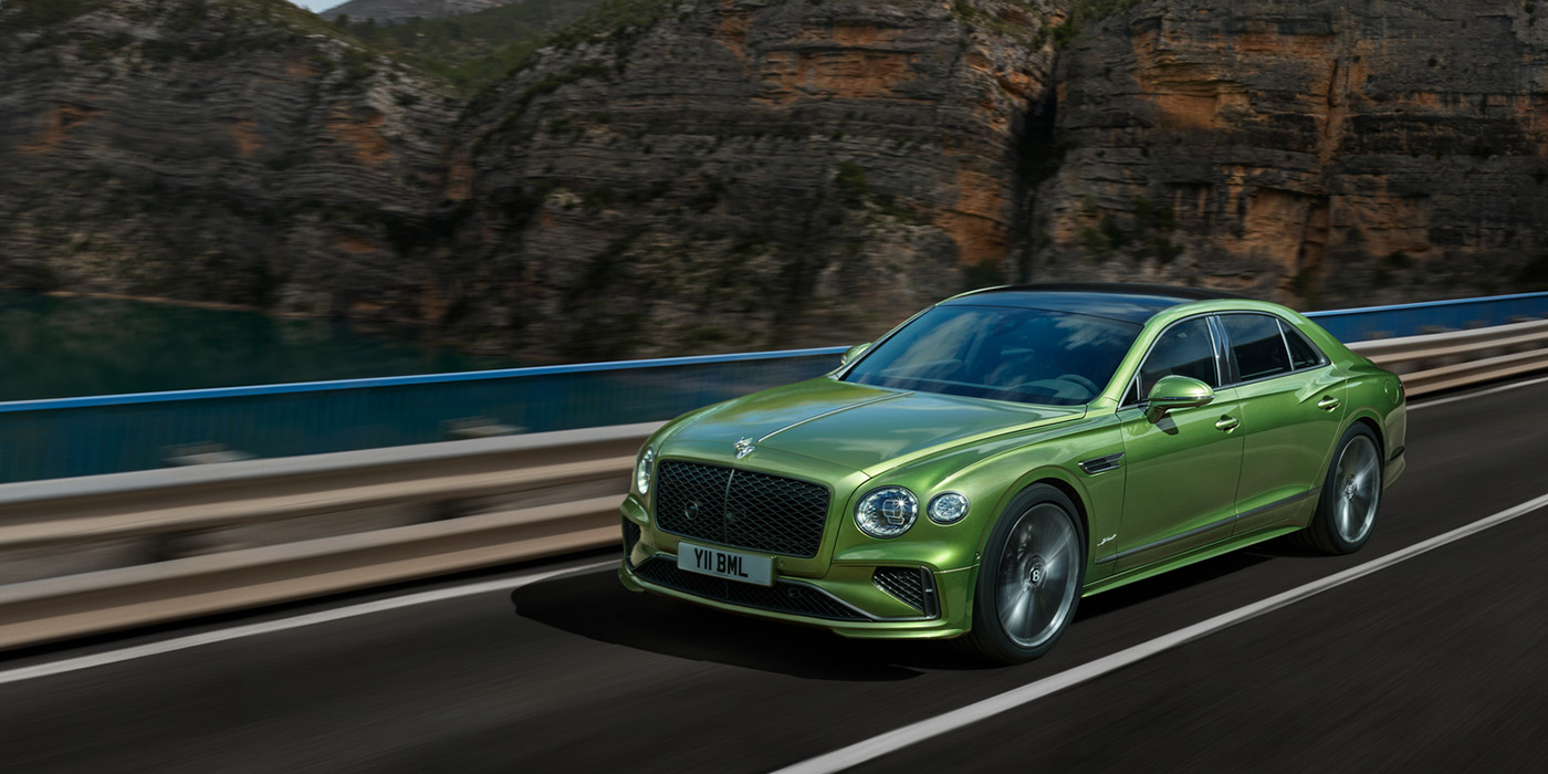 Bentley Hatfield Bentley New Flying Spur Speed v8 hybrid sedan driving dynamically on a mountain road in Tourmaline Green paint