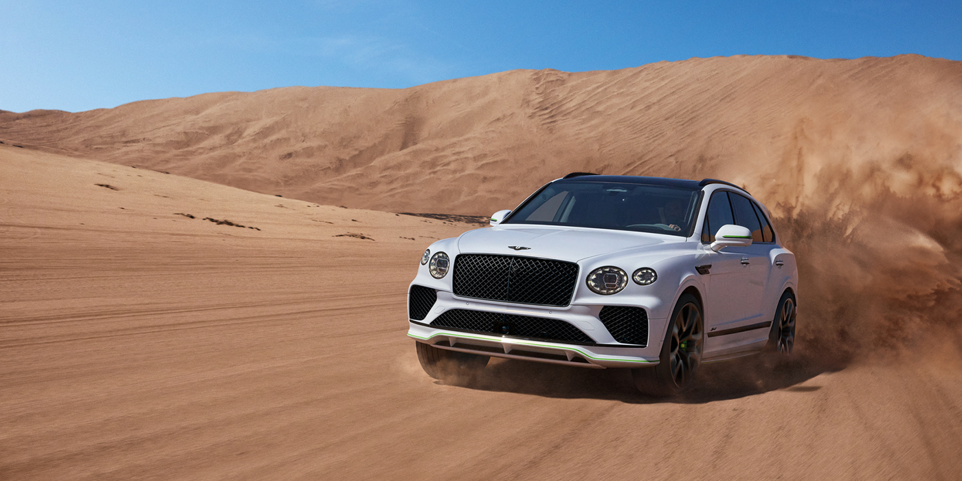 Bentley Hatfield Bentley Bentayga Speed SUV front three quarter in Snow Quarts Pearlescent by Mulliner white paint driving dynamically through the desert