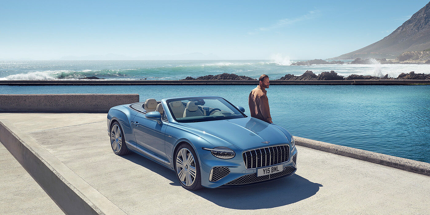 Bentley Hatfield New Bentley Continental GTC Azure convertible front view in Light Windsor blue paint with 22 inch ten spoke wheels parked by the sea in the sunshine