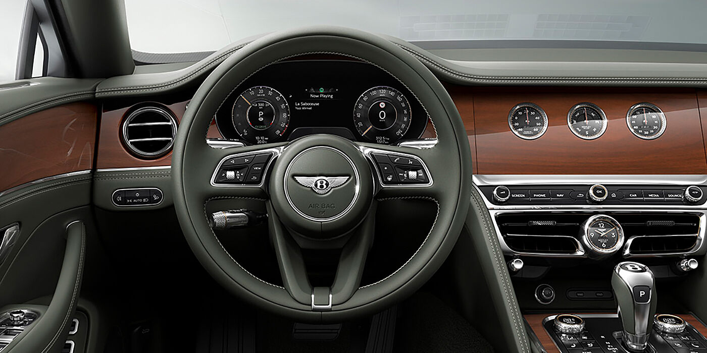 Bentley Hatfield New Bentley Flying Spur sedan front cabin in Cumbrian Green hide and Crown Cut walnut veneer showing steering wheel and Rotating Display with three clocks on face