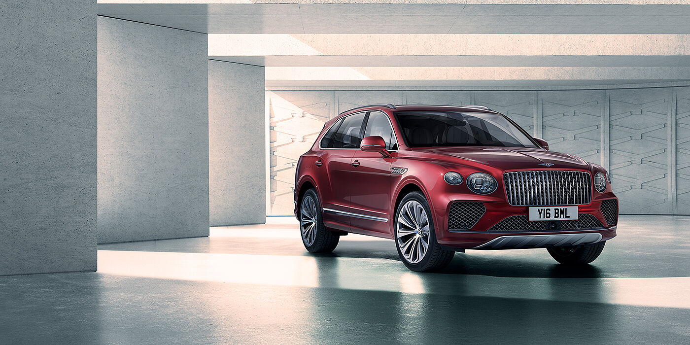 Bentley Hatfield Bentley Bentayga Atelier Edition SUV in Rubino Red paint front three quarter against textured concrete wall