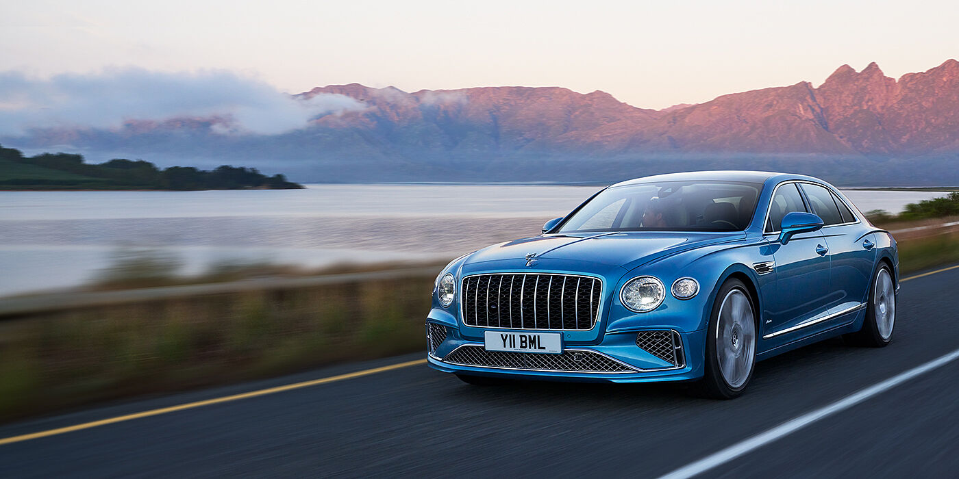 Bentley Hatfield New Bentley Flying Spur Azure sedan in Light windsor blue paint by Mulliner, with 22 inch Azure wheels and chrome straight vaned grille driving on a mountain road