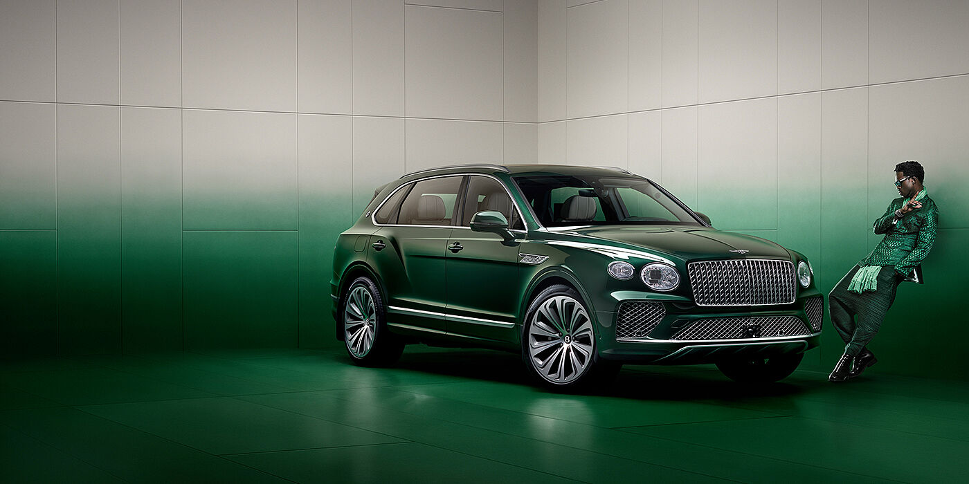 Bentley Hatfield Wisdom K leans against wall next to Bentley Bentayga Extended Wheelbase Atelier Edition SUV in Light Emerald green paint