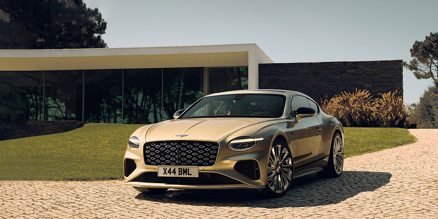 Bentley Hatfield Bentley Continental GT Mulliner coupe front three quarters in Patina paint parked outside a glass fronted building with a grass lawn behind it