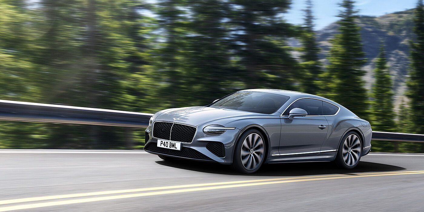 Bentley Hatfield New Bentley Continental GT coupe in Silverlake paint and 22 inch ten-spoke wheels, driving dynamically on a tree-lined road in the sunshine