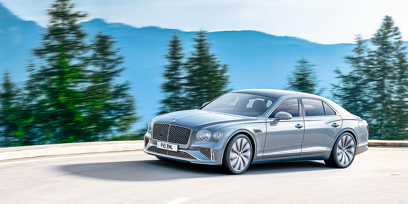 Bentley Hatfield New Bentley Flying Spur sedan side view in Silverlake paint with ten spoke wheels and chrome matrix grille driving dynamically on a mountain road