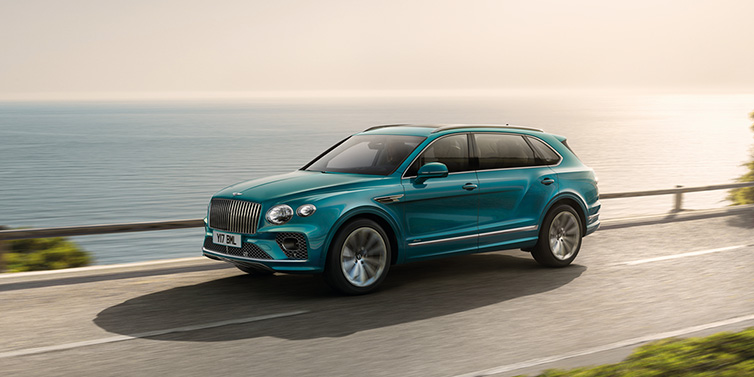 Bentley Hatfield Bentley Bentayga Extended Wheelbase Azure SUV in Topaz blue paint driving dynamically by the ocean