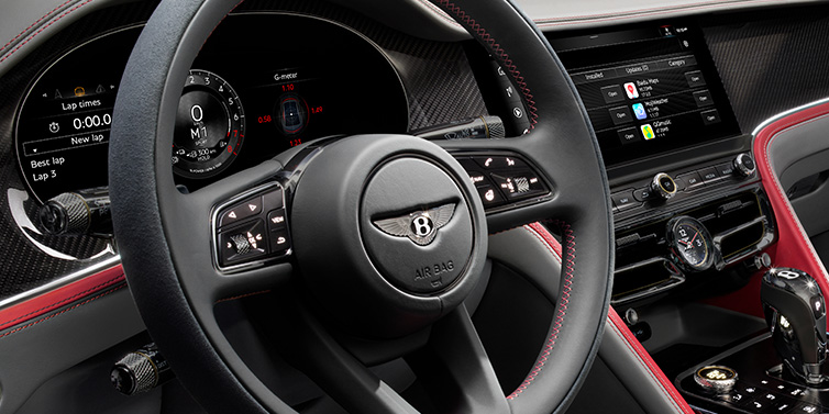 Bentley Hatfield Bentley Flying Spur Speed sedan front interior detail showing steering wheel and driver screens surrounded with Hotspur red and Gravity Grey hides